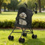 Small white dog in a black foldable pet stroller at a park