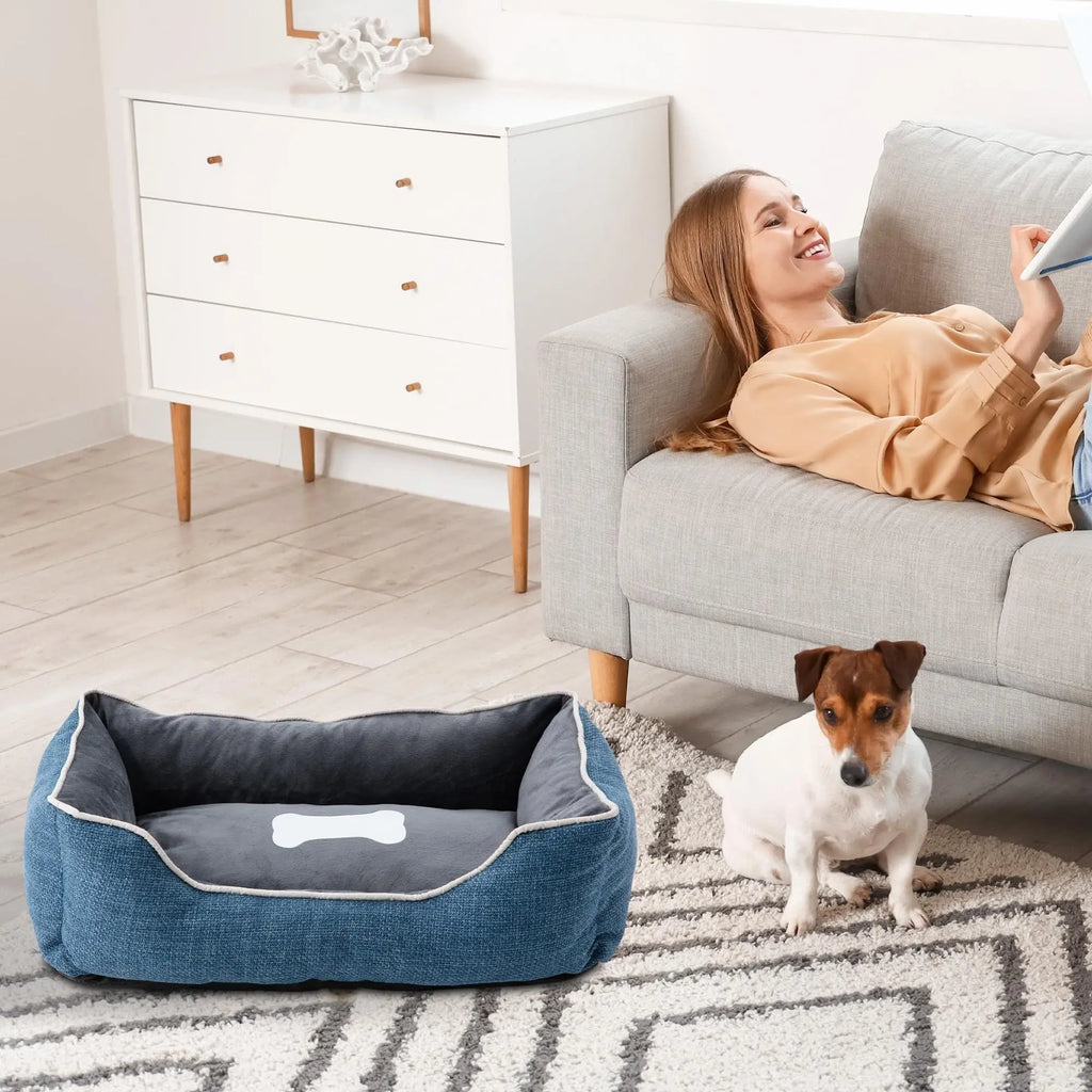 Blue pet bed beside a sofa with a small dog