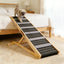 Small dog using a wooden ramp beside a bed
