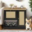 Black dog feeding cabinet with rattan-style doors beside a corgi in a living room