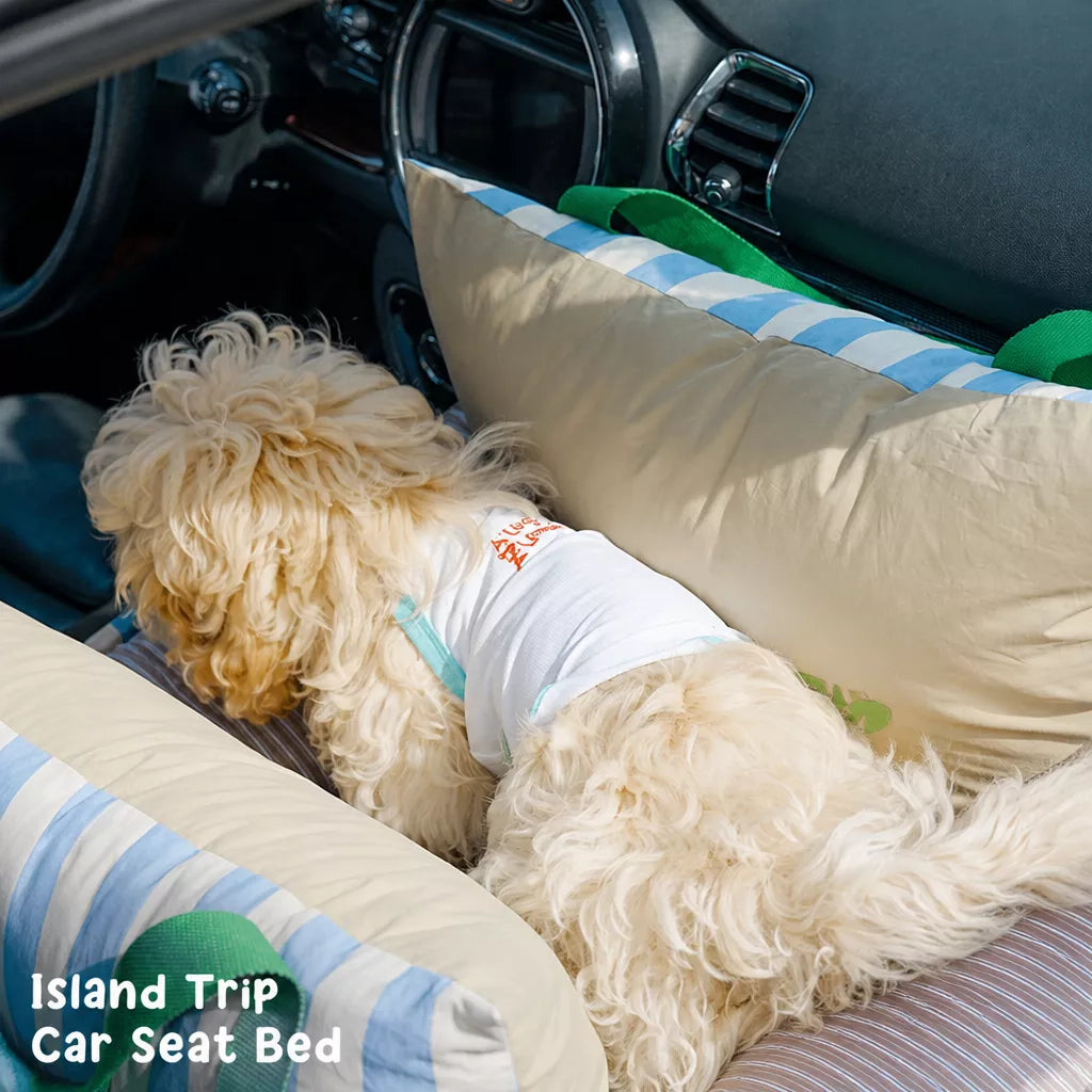 Dog reclining in striped car bed on vehicle seat