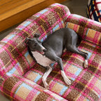 Dog relaxing in pink plaid pet sofa