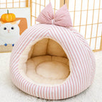 Pink striped pet cave bed with bow in a home setting