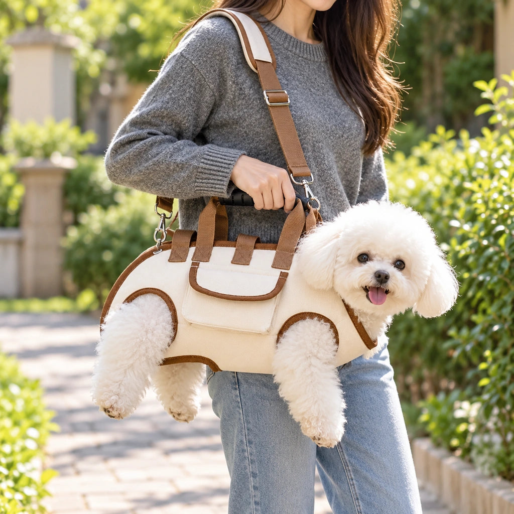 Small white dog supported in the cream and brown horizontal leg-out shoulder carrier outdoors Main image