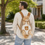 Beige and brown pet carrier backpack worn on the back with an orange cat