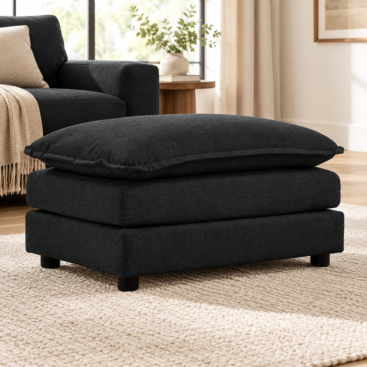 Black Chenille Cushioned Ottoman — beside a living-room sofa